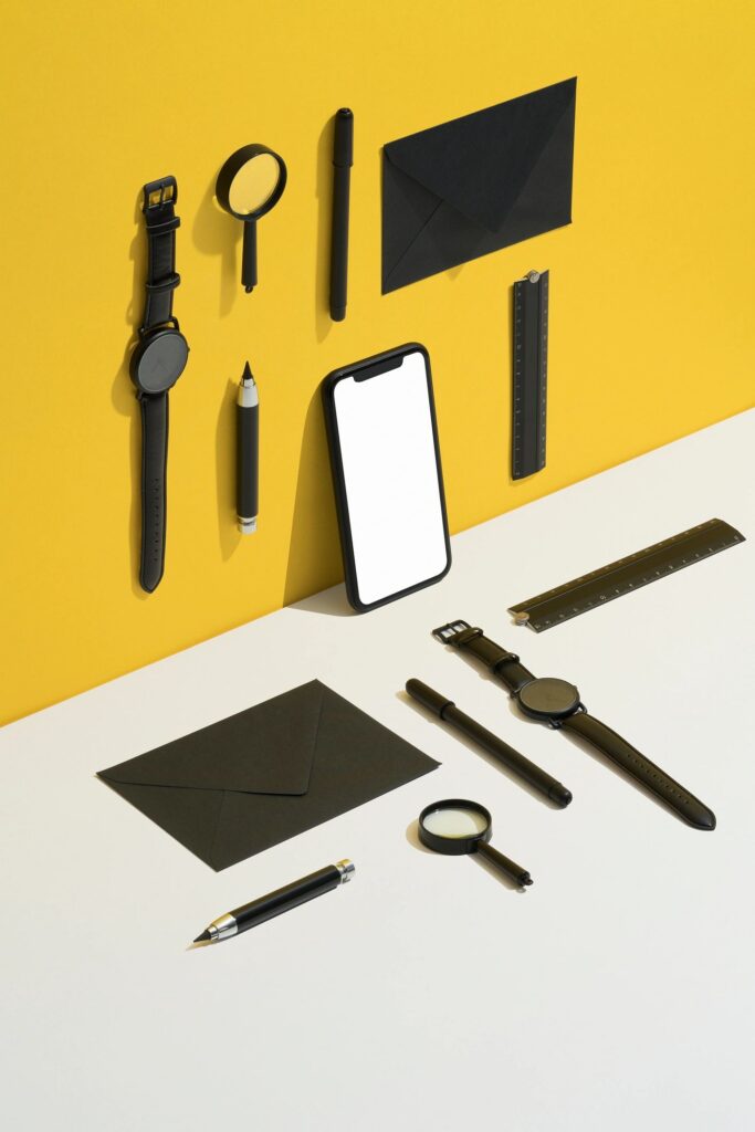 Black personal accessories, stationary flat lay on yellow and white background