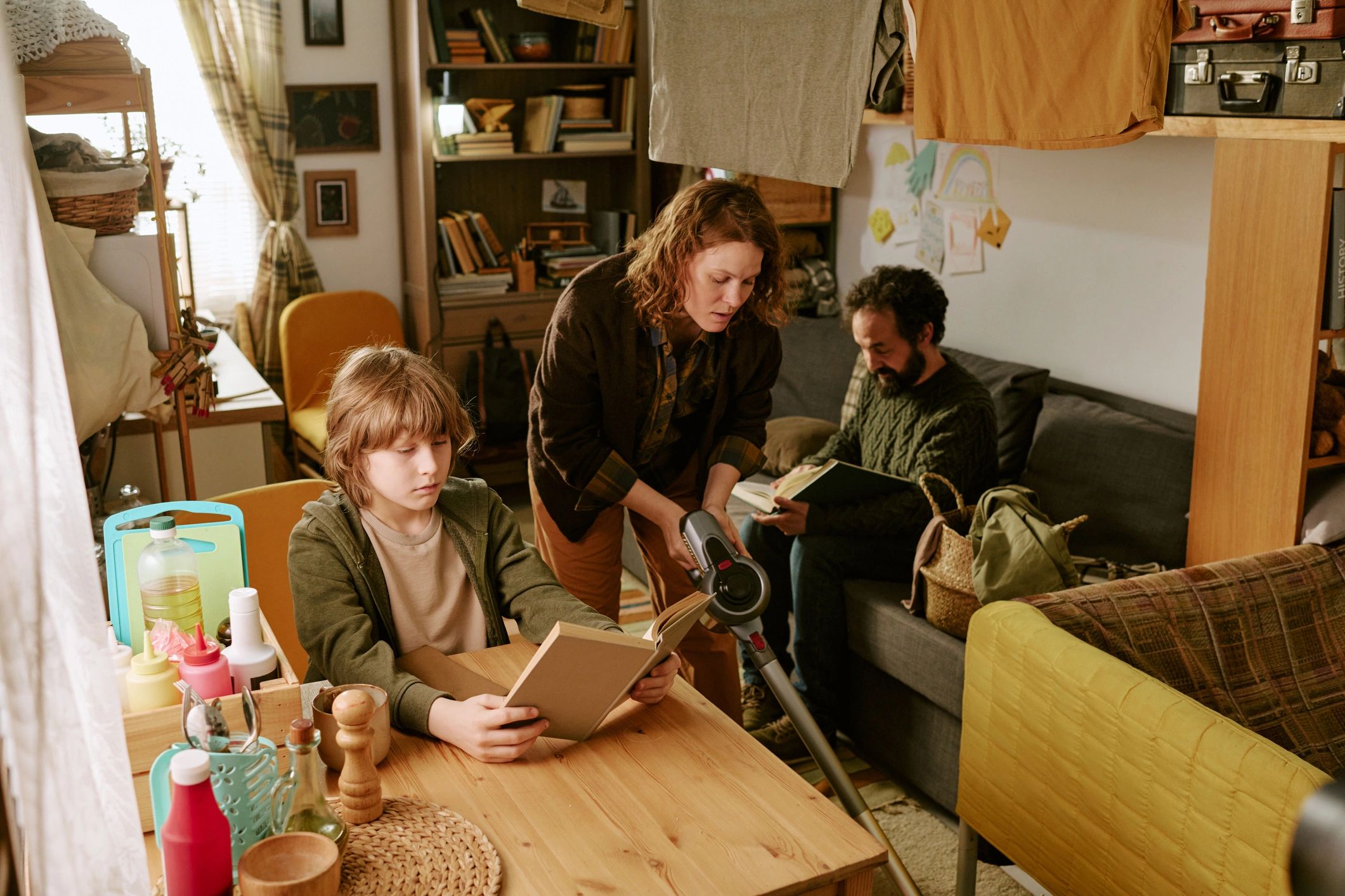 Child reading at home with family nearby